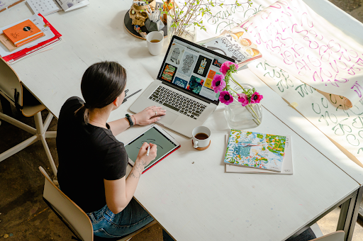 woman working at a desk with flowers and laptop on it