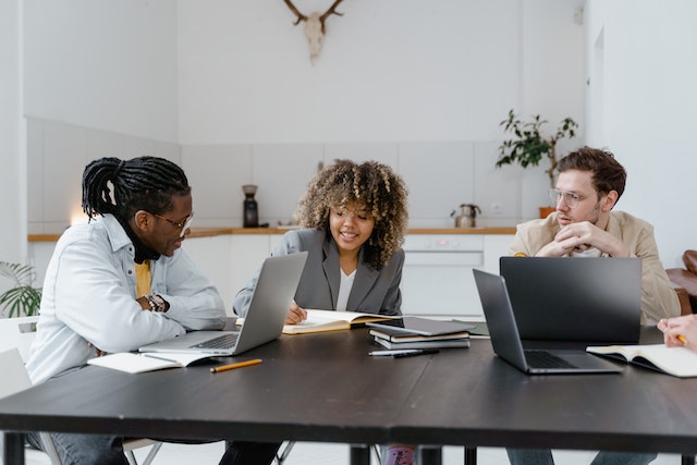 three colleagues working at a desk and sharing ideas