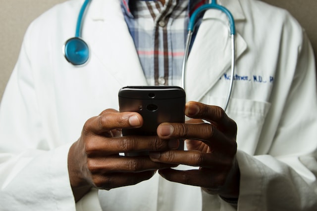 doctor using a smartphone with a stethoscope around his neck