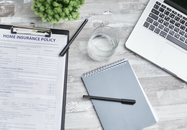 overhead view of a table with a laptop on one side and a home insurance policy on the other side