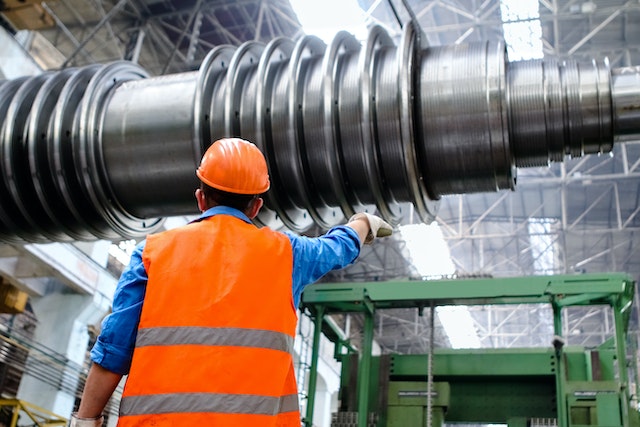 manufacturer in a high-vis outfit guiding a large drill into place