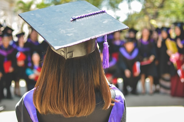 woman in a purple graduation robe looking towards her classmates