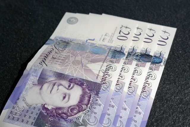 top down perspective of four purple twenty pound notes with Queen Elizabeth on the front