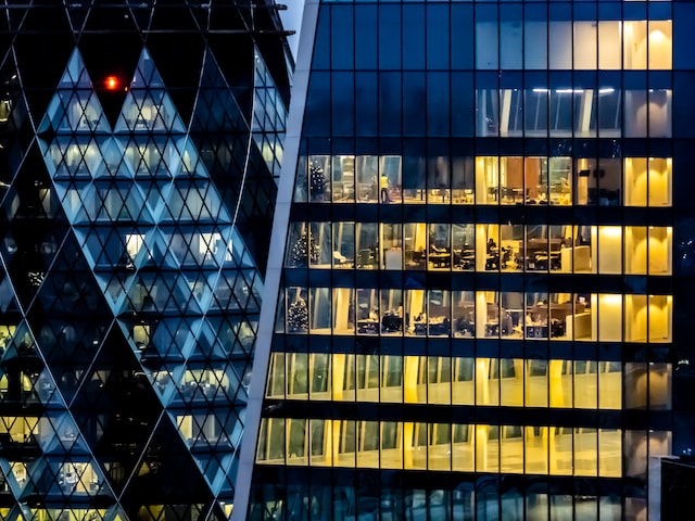 exterior view of a large London office building at night that shows people working through lit windows