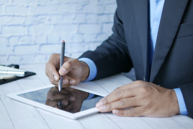 man in a suit working on a digital tablet with a pen