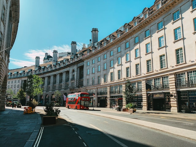 a curved West London street with a red doubled decker bus in the background