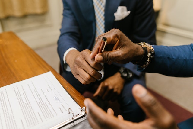 man passing a pen to another man to sign a tenancy agreement