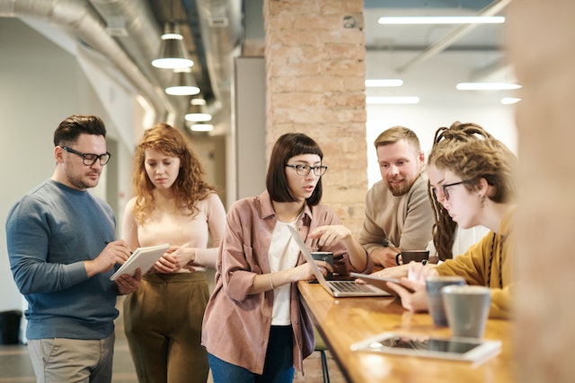 five colleague discussing work at a bench in a coworking space