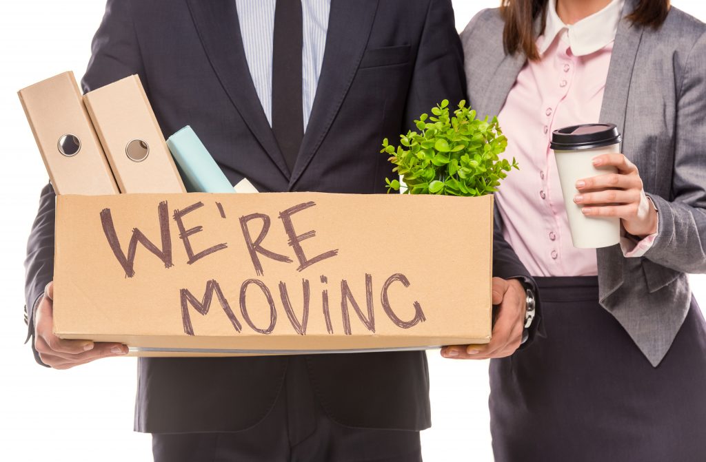 Young happy businessman and a business woman with boxes for moving into a new office. Studio shot, isolated on a white background