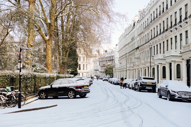 Daytime view down a prestigious Mayfair street in the height of winter, with leafless trees on the left and refurbished historic three-storey buildings lining the right side. The street and cars and bicycles parked alongside are all dusted in snow. Image at LondonOfficeSpace.com.