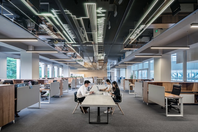 Three colleagues work together seated at a long communal desk in the centre of their modern Shoreditch office. Image at LondonOfficeSpace.com.