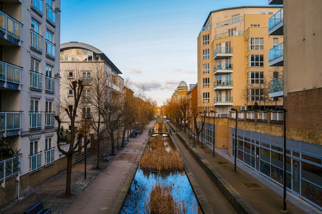 A view down one of the canals of Canada Water in London during the daytime. Footpaths line the canal and buildings rise to either side. Image at LondonOfficeSpace.com.