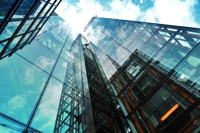 A ground-up daytime view up the side of a shiny, glass-fronted skyscraper towards a cloud-strewn sky. Image at LondonOfficeSpace.com.